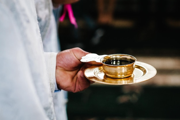 El sacerdote bendice y sostiene la copa del vino de la sangre de Dios El sacerdote celebra una misa en la ceremonia de boda tradicional de la iglesia Copa sagrada para la ceremonia de boda