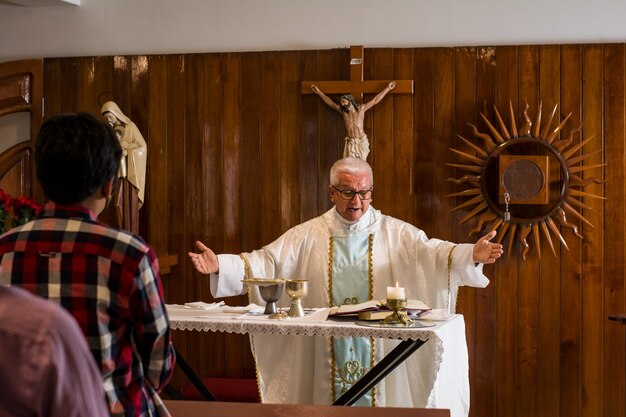 Sacerdote católico latino predicando en la iglesia durante la liturgia en diferentes poses