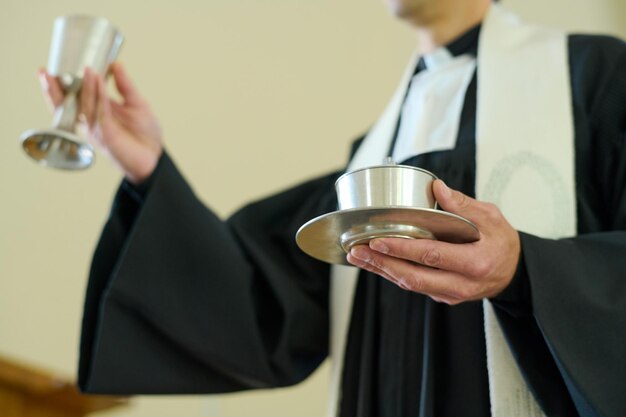Sacerdote católico sosteniendo copas con vino y panes sin levadura para la oblación