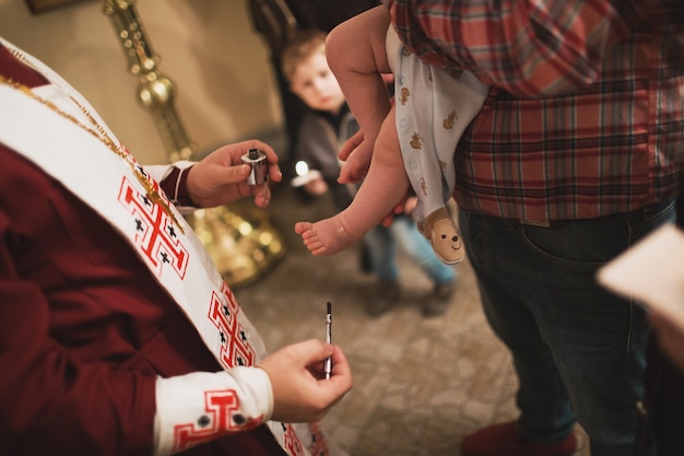 Foto sacerdote cristiano ortodoxo y niño en la iglesia. la unción del rito de la ceremonia de la epifanía.