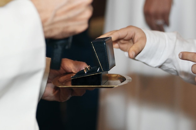 El sacerdote en la iglesia pasa los anillos de boda al