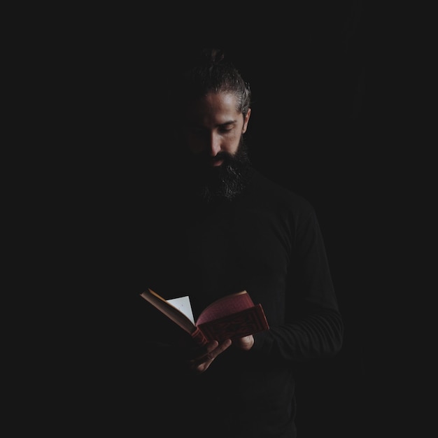 Sacerdote lendo a Bíblia contra um fundo preto