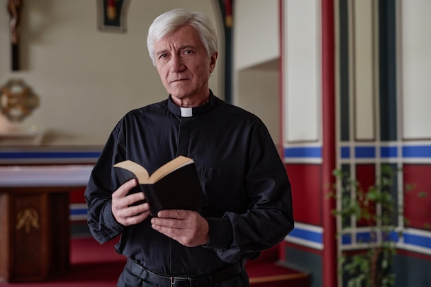 Sacerdote mayor con biblia en iglesia