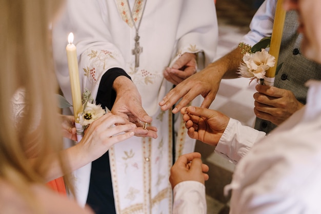 Sacerdote ofrece los anillos a los novios con velas en sus manos
