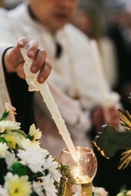 Foto sacerdote relámpago vela y sosteniendo cruz durante el santo matrimonio en la iglesia santo momento espiritual llama de vela