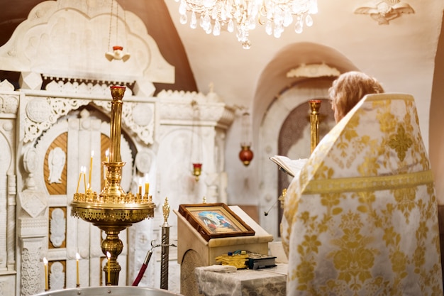 Sacerdote vistiendo túnica de oro en la ceremonia en la iglesia de la catedral cristiana, evento sacramental sagrado.
