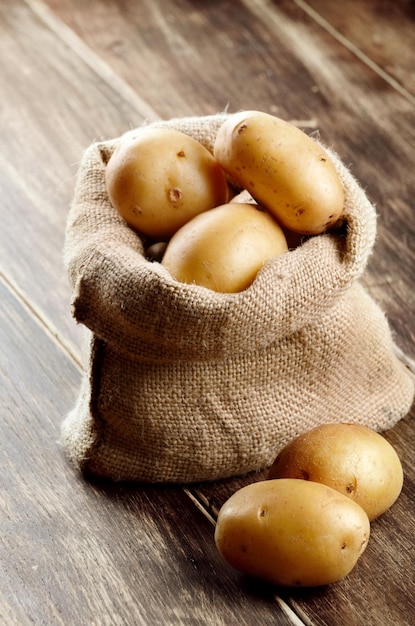 Saco de arpillera con patatas en la mesa de madera