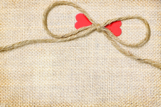 El saco de cuerda grande con papel par corazón rojo sobre fondo marrón saco tiene espacio de copia para p
