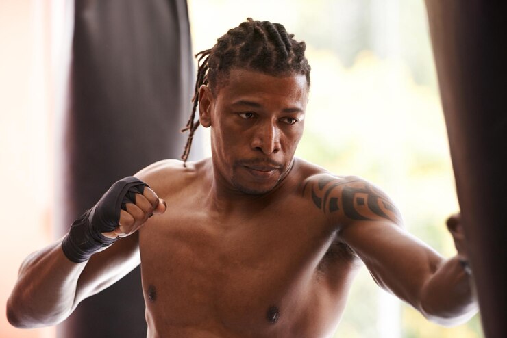 Foto saco de boxe de fitness e homem negro sério no ginásio para exercício desafio de boxe ou treinamento de competição músculo de potência e campeão de boxe no treino com confiança luta e energia no clube esportivo
