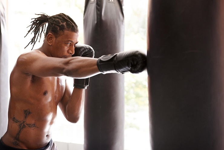 Foto saco de boxe muscular e homem preto no ginásio para exercício desafio de boxe ou treinamento de competição potência aptidão e boxeador campeão sério no treino com confiança luta e energia no clube esportivo