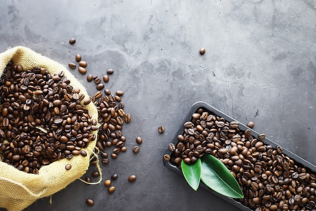 Saco de café. Grãos de café torrados na mesa. Grãos de café com folhas verdes para cozinhar.