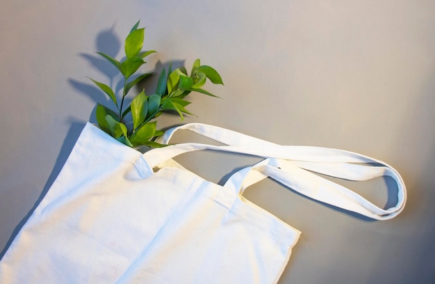 Saco de compras creme branco para o seu projeto em um fundo cinza ecologicamente correto sem desperdício com espaço de cópia Ramos de eucalipto