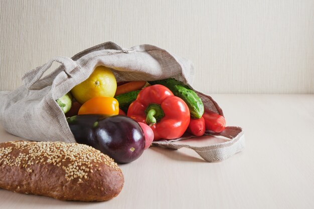 Saco de compras de malha reutilizável ecologicamente correto com frutas e vegetais na mesa, conceito de desperdício zero