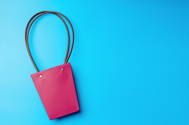 Saco de compras de papel com alças redondas em um fundo azul Flatlay com espaço para copiar Bolsa rosa sólida na moda