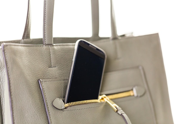 Foto saco de couro da mulher elegante com telefone inteligente em um fundo branco e isolado.