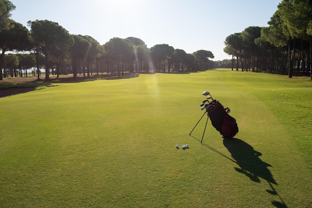 saco de golfe no curso com taco e bola na frente no belo nascer do sol