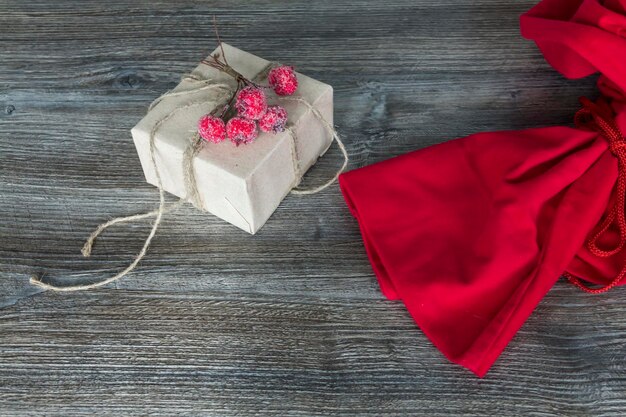 Saco de Papai Noel vermelho e presente embalado em embalagens artesanais em um fundo de superfície de madeira
