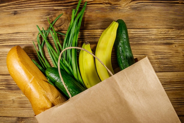 Saco de papel com comida diferente na mesa de madeira Vista superior Conceito de compras de supermercado