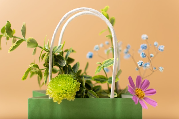 Saco de papel com lindas flores no jardim de verão e plantas em fundo bege