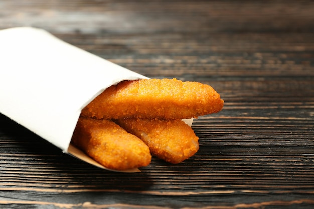 Saco de papel com palitos de queijo em fundo de madeira