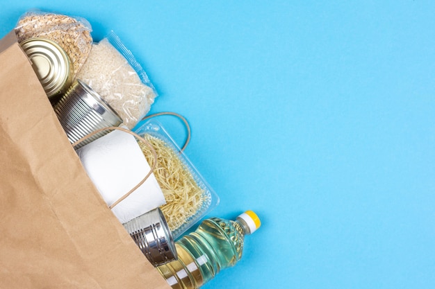 Saco de papel com um suprimento de alimentos de crise pelo período de isolamento de quarentena em um fundo azul