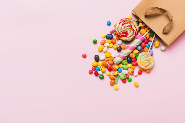 Saco de presente de papel comercial no canto cheio de doces tradicionais variados caindo sobre fundo colorido com espaço de cópia Conceito de venda de boas festas