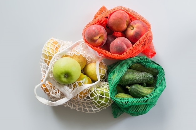 Saco de rede três compras com frutas e legumes.