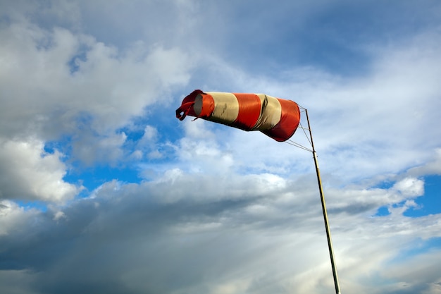 Saco de vento de meteorologia para navegação marítima. A cata-vento vermelha e branca sopra contra um céu azul