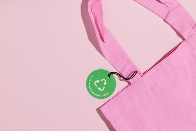 Sacola de compras ecológica rosa e etiqueta de papel verde com inscrição Feito de materiais reciclados Mockup