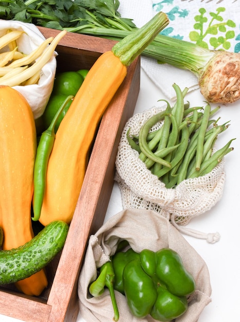 Sacos de bolsas ecológicas y una caja de almacenamiento de madera Tomates pimientos calabacín pepinos frijoles Concepto de cero residuos