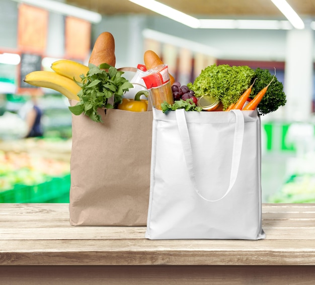 Sacos de compras com legumes e frutas na mesa