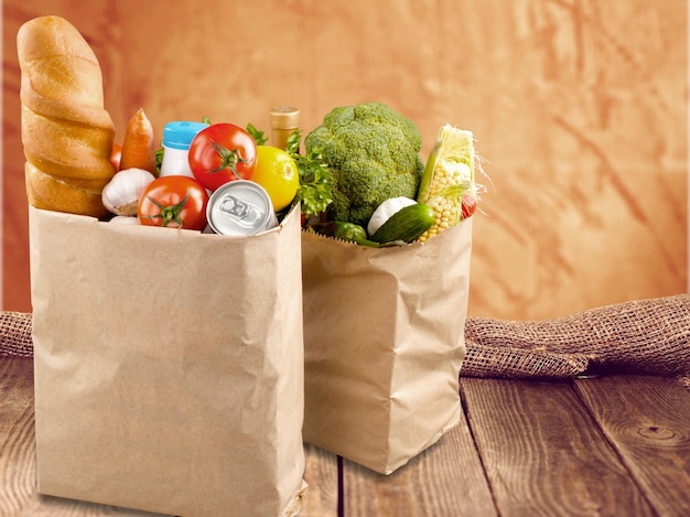 Sacos de compras com produtos de mercearia na mesa de madeira