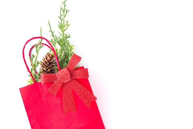 Sacos de compras vermelhos e verdes com decoração de Natal, galhos de árvores de abeto, arco festivo isolado no espaço de cópia de vista superior de fundo branco. Conceito de venda de natal