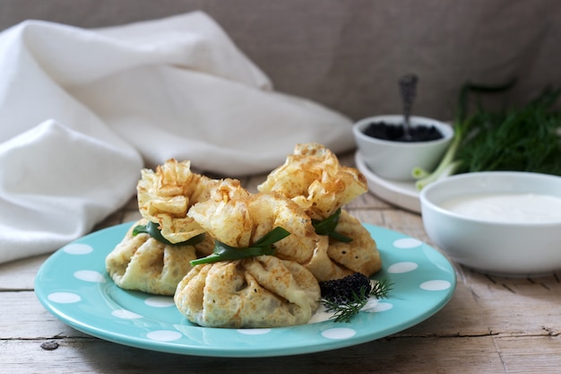 Sacos de panquecas recheadas com arenque, servido com caviar, creme de leite e endro em um fundo de madeira. Estilo rústico.