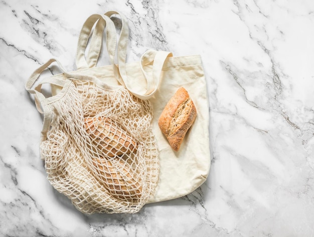 Sacos e pães ecológicos reutilizáveis em uma vista superior de fundo de mármore claro