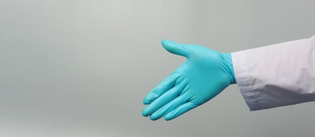 Sacudida de la mano use una bata de médico y un guante médico azul sobre fondo gris. Estudio de rodaje.