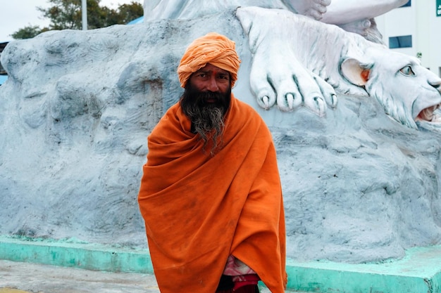 Sadhu indiano em frente à estátua de Shiva em Haridwar