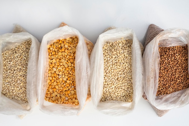 Säcke mit Gerstenkörnern, Buchweizen und Spalterbsen stehen auf einem weißen Tisch Das Konzept des Lebensmittelhandels