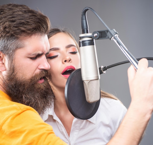 Sängerpaar spielt ein Lied mit einem Mikrofon während der Aufnahme in einem Musikstudio.