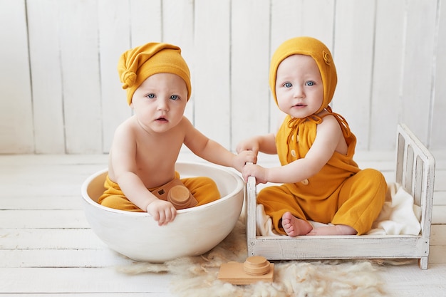 Säuglingszwillinge in orangefarbenen Anzügen posieren