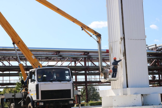 Säulen mit Spezialtechnik reparieren Arbeiter am Kran reparieren eine große weiße Säule