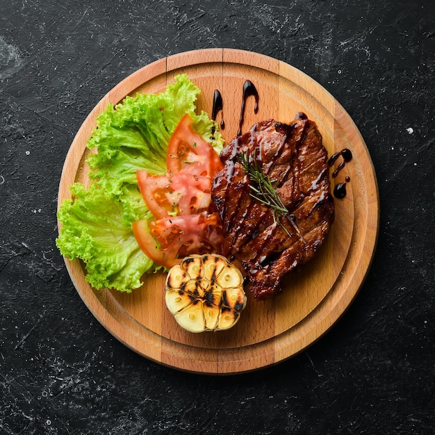 Saftig gebackenes Schweinesteak mit Gemüse auf dem Brett Draufsicht