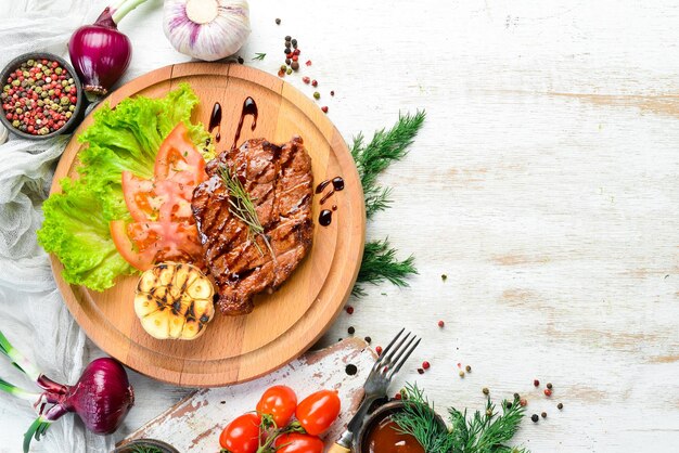 Saftig gebackenes Schweinesteak mit Gemüse auf dem Brett Draufsicht