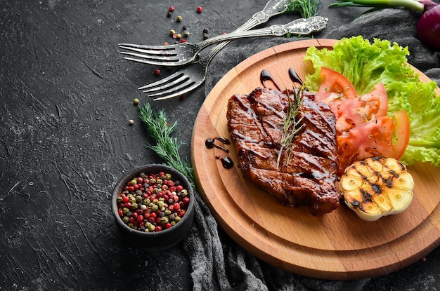 Saftig gebackenes Schweinesteak mit Gemüse auf dem Brett Draufsicht