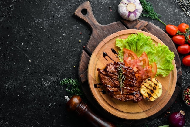 Saftig gebackenes Schweinesteak mit Gemüse auf dem Brett Draufsicht