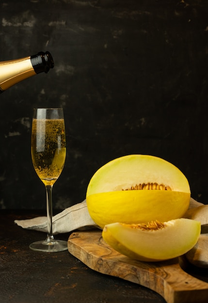 saftig gelbe kleine Melone mit einem Glas Champagner auf dem Tisch