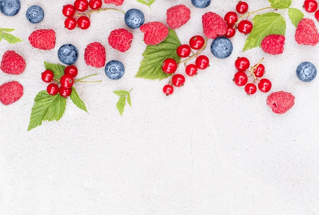 Foto saftige beeren von himbeeren, heidelbeeren und roten johannisbeeren auf betonuntergrund