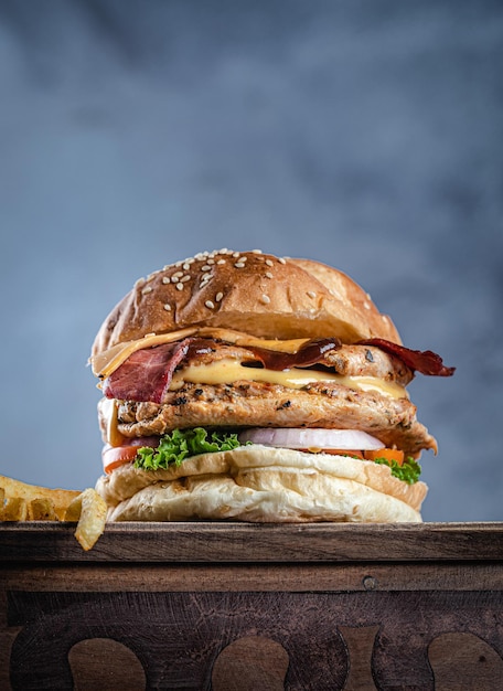 Saftige doppelte Hühnchen- und Speckkäse-Burger-Vorderansicht auf Vintage-Hintergrund