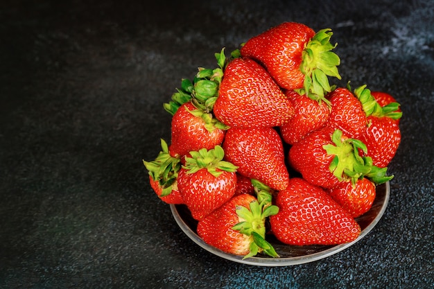 Saftige Erdbeeren in Teller auf dunkler Oberfläche