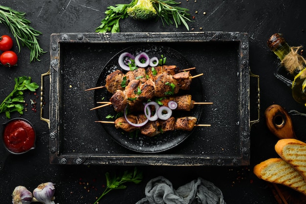 Saftige Fleischspieße in einem schwarzen Teller. Grillen, Kebab. Ansicht von oben. Freier Kopienraum.